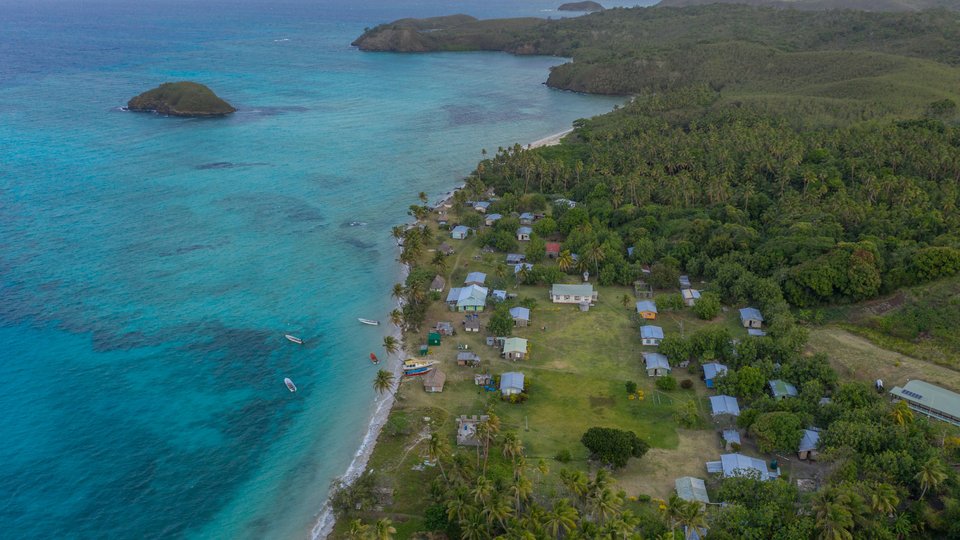 Aerial view of a fishing community along the coast nestled up against clear blue waters